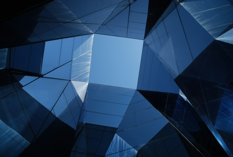 View of blue sky looking through prism of glass buildings